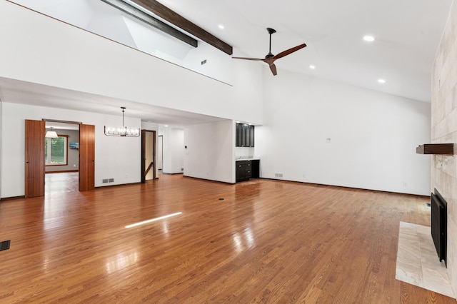 1775 Lexington Ave S Unit 26, Lilydale, MN 55118 - unfurnished living room featuring a tile fireplace, ceiling fan, a chandelier, high vaulted ceiling, and light wood-style flooring