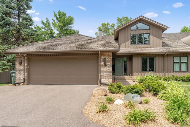 1775 Lexington Ave S Unit 26, Lilydale, MN 55118 - view of front of home featuring board and batten siding, asphalt driveway, a garage, a chimney, and brick siding