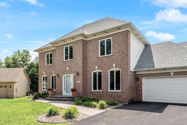 2227 Stone Creek Ln E, Chanhassen, MN 55317 - view of front facade featuring a garage, brick siding, driveway, roof with shingles, and a front yard