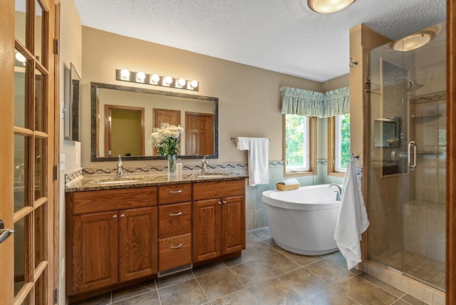 2227 Stone Creek Ln E, Chanhassen, MN 55317 - bathroom featuring a stall shower, a freestanding tub, double vanity, a textured ceiling, and tile patterned floors