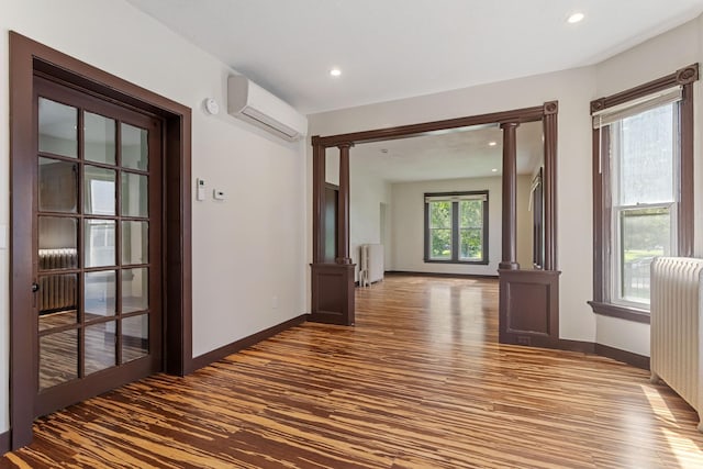 981 Bayless Ave, Saint Paul, MN 55114 - hallway with a wall unit AC, radiator heating unit, wood finished floors, decorative columns, and recessed lighting