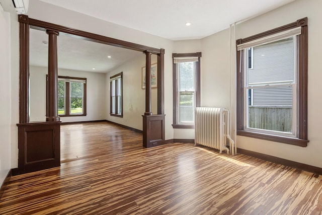 981 Bayless Ave, Saint Paul, MN 55114 - empty room with radiator heating unit, dark wood-style floors, healthy amount of natural light, an AC wall unit, and recessed lighting