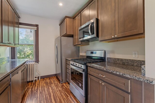 981 Bayless Ave, Saint Paul, MN 55114 - kitchen featuring appliances with stainless steel finishes, radiator heating unit, dark wood-style floors, dark stone countertops, and recessed lighting