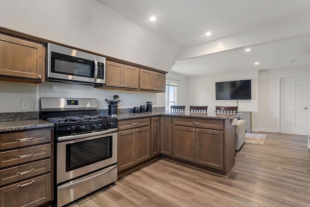 981 Bayless Ave, Saint Paul, MN 55114 - kitchen featuring appliances with stainless steel finishes, a peninsula, light wood-style flooring, recessed lighting, and dark stone counters