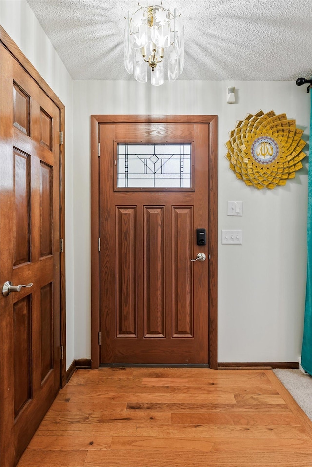 7795 Van Buren St NE, Spring Lake Park, MN 55432 - foyer entrance featuring a textured ceiling, a chandelier, and light wood-style floors