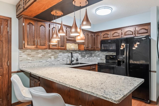 7795 Van Buren St NE, Spring Lake Park, MN 55432 - kitchen featuring black appliances, a peninsula, decorative backsplash, a breakfast bar area, and decorative light fixtures
