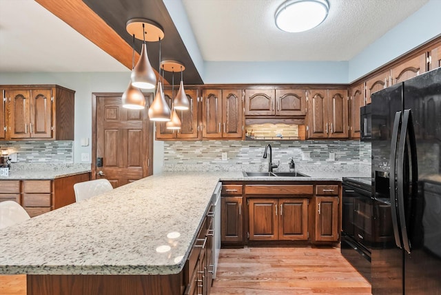 7795 Van Buren St NE, Spring Lake Park, MN 55432 - kitchen with black appliances, a peninsula, backsplash, light wood finished floors, and light stone countertops