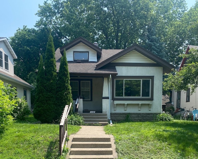 3447 38th Ave S, Minneapolis, MN 55406 - view of front of home featuring covered porch, a shingled roof, stucco siding, and a front lawn