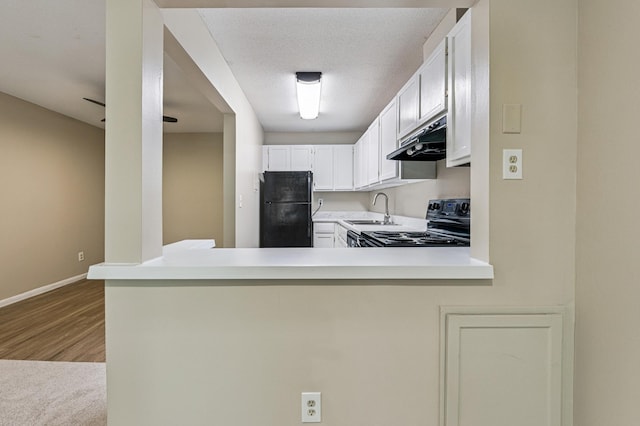 10311 Cedar Lake Rd Unit 210, Minnetonka, MN 55305 - kitchen featuring black appliances, under cabinet range hood, light countertops, a peninsula, and white cabinetry