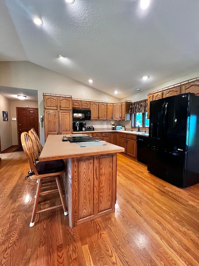 4095 125th St SE, Granite Falls, MN 56241 - kitchen with black appliances, lofted ceiling, light wood-style floors, a kitchen island, and brown cabinetry