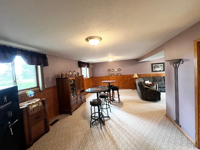 4095 125th St SE, Granite Falls, MN 56241 - dining space featuring light carpet, wainscoting, wooden walls, and a textured ceiling