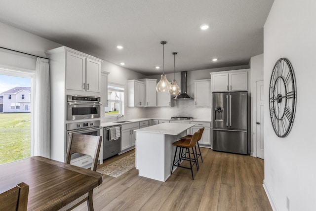 1959 Tamarack Rd, Carver, MN 55315 - kitchen featuring appliances with stainless steel finishes, wall chimney exhaust hood, a center island, light countertops, and a kitchen breakfast bar