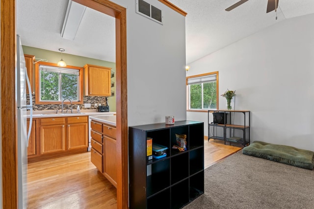 3902 Strathmore Ln SE, Rochester, MN 55904 - kitchen featuring vaulted ceiling, a ceiling fan, light countertops, tasteful backsplash, and freestanding refrigerator