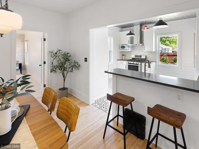 3201 Xenwood Ave S, Saint Louis Park, MN 55416 - kitchen with dark countertops, stainless steel gas range oven, a kitchen breakfast bar, and wall chimney exhaust hood