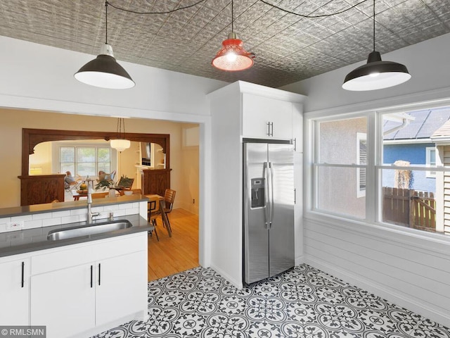 3201 Xenwood Ave S, Saint Louis Park, MN 55416 - kitchen with stainless steel fridge, dark countertops, white cabinetry, hanging light fixtures, and an ornate ceiling