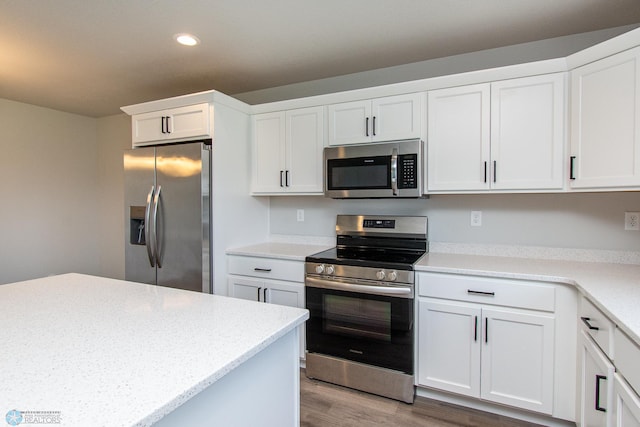 1449 68th Ave S, Fargo, ND 58104 - kitchen featuring stainless steel appliances, recessed lighting, wood finished floors, white cabinets, and light stone counters
