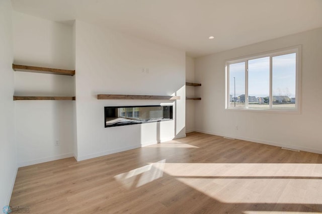 419 Reese Way, Mapleton, ND 58059 - unfurnished living room featuring a glass covered fireplace, wood finished floors, and recessed lighting
