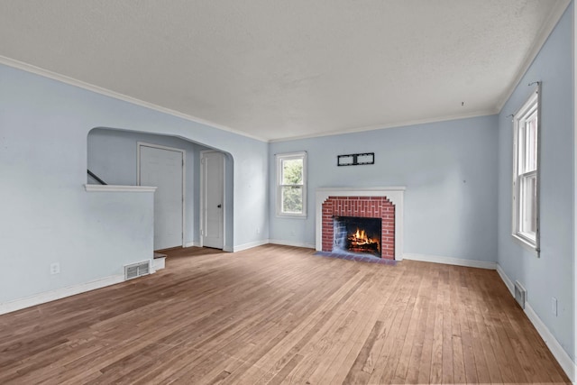 1289 Galtier St, Saint Paul, MN 55117 - unfurnished living room with hardwood / wood-style flooring, arched walkways, a brick fireplace, ornamental molding, and a textured ceiling