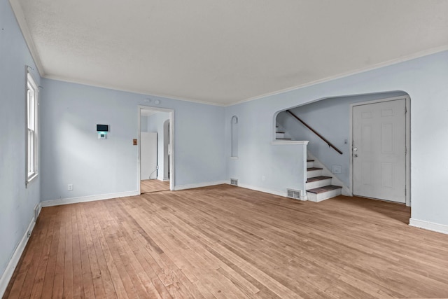 1289 Galtier St, Saint Paul, MN 55117 - unfurnished living room featuring arched walkways, light wood-style flooring, ornamental molding, and stairway
