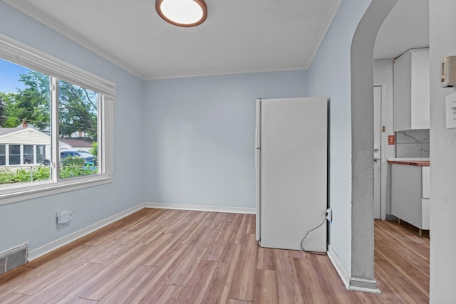 1289 Galtier St, Saint Paul, MN 55117 - unfurnished bedroom featuring freestanding refrigerator, light wood-style floors, arched walkways, and crown molding