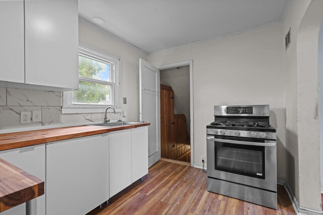 1289 Galtier St, Saint Paul, MN 55117 - kitchen with gas range, wooden counters, white cabinetry, light wood-style floors, and ornamental molding