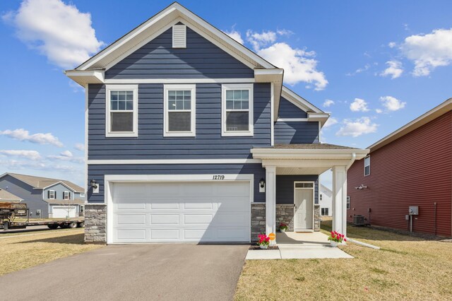 12719 Erskin St NE, Blaine, MN 55449 - view of front of home with an attached garage, stone siding, a front lawn, and asphalt driveway