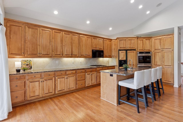 343 Waycliffe Dr N, Wayzata, MN 55391 - kitchen featuring appliances with stainless steel finishes, lofted ceiling, decorative backsplash, dark stone countertops, and a breakfast bar