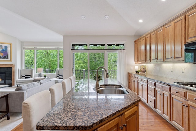 343 Waycliffe Dr N, Wayzata, MN 55391 - kitchen featuring vaulted ceiling, stainless steel gas cooktop, an island with sink, light wood finished floors, and recessed lighting
