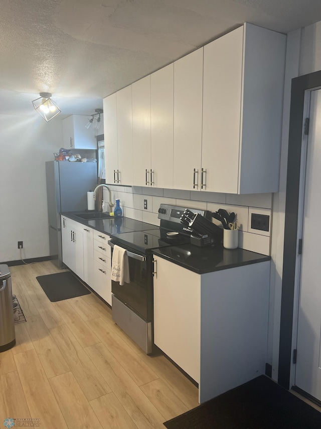 1822 7th Ave S, Fargo, ND 58103 - kitchen featuring stainless steel electric range oven, light wood-style flooring, dark countertops, white cabinetry, and a textured ceiling