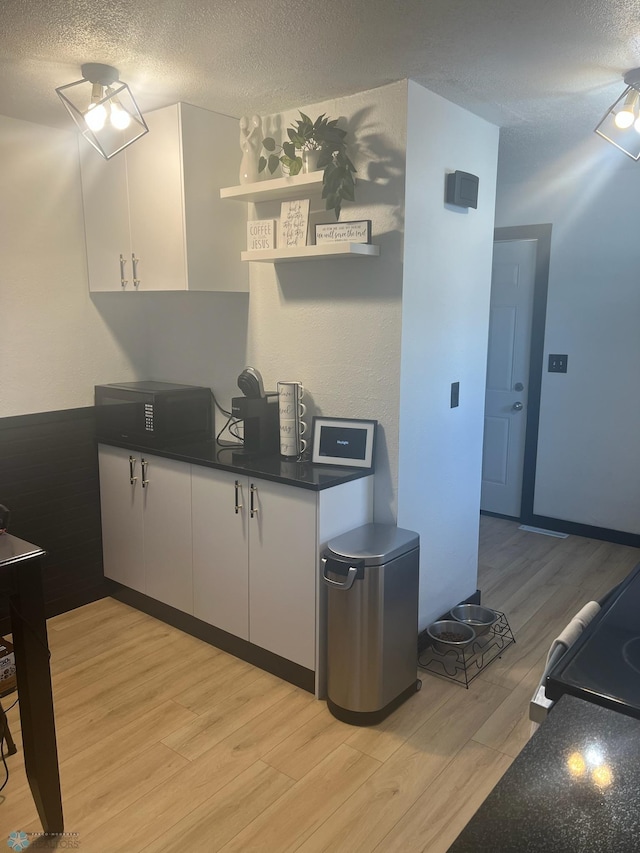 1822 7th Ave S, Fargo, ND 58103 - kitchen with dark countertops, light wood finished floors, white cabinets, a textured ceiling, and open shelves