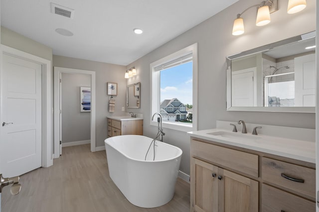 15560 110th Ave N, Dayton, MN 55369 - full bathroom featuring a shower stall, a freestanding bath, two vanities, wood finished floors, and recessed lighting