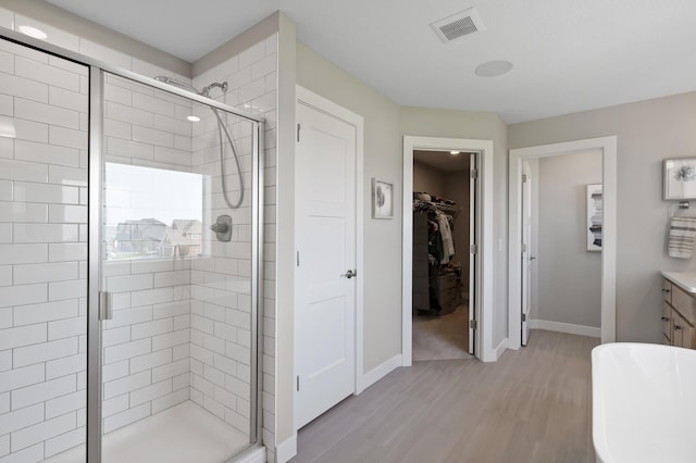 15560 110th Ave N, Dayton, MN 55369 - bathroom with a shower stall, wood finished floors, a walk in closet, and a freestanding tub