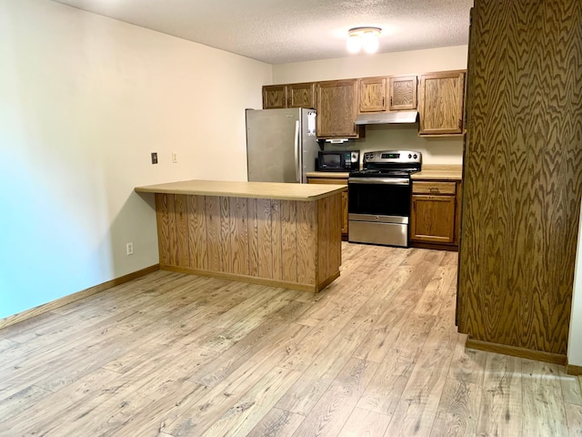 2419 25 1/2 Ave S Unit 205, Fargo, ND 58103 - kitchen featuring appliances with stainless steel finishes, under cabinet range hood, light wood finished floors, a peninsula, and light countertops