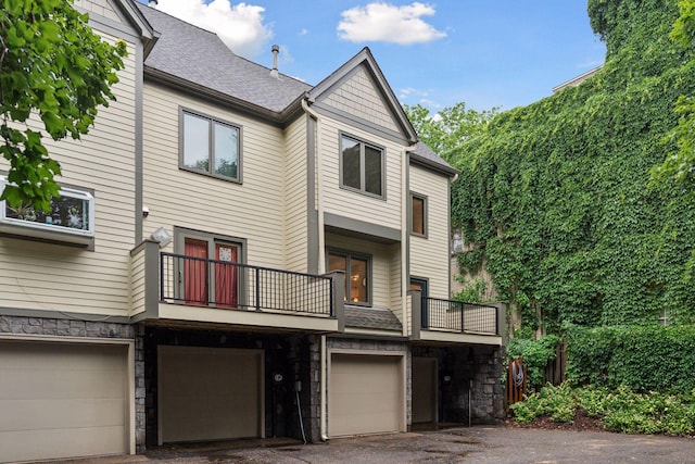 729 Summit Ave, Saint Paul, MN 55105 - rear view of property featuring stone siding, a balcony, a garage, driveway, and a shingled roof