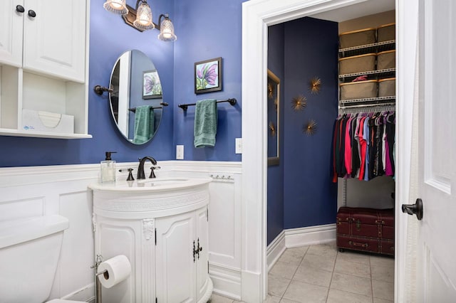 977 Portland Ave Unit 1, Saint Paul, MN 55104 - bathroom with tile patterned floors, vanity, a spacious closet, and wainscoting
