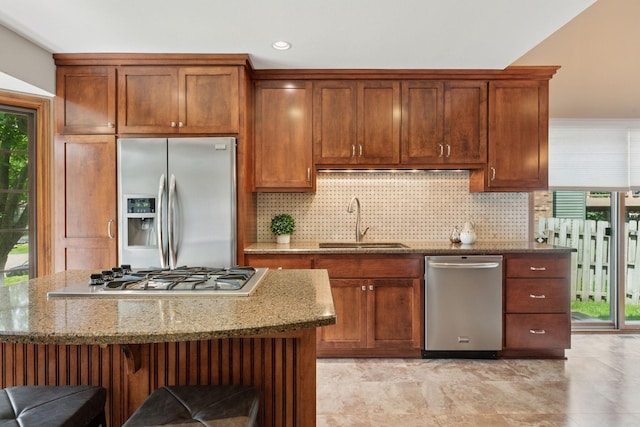 7516 Colorado Ave N, Brooklyn Park, MN 55443 - kitchen featuring appliances with stainless steel finishes, light stone counters, decorative backsplash, a kitchen island, and a kitchen breakfast bar