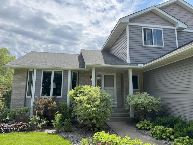 402 14th St, Delano, MN 55328 - view of front facade with brick siding, covered porch, and roof with shingles