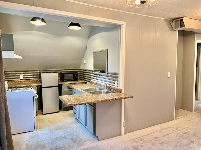 410 10th St SW, Willmar, MN 56201 - kitchen with freestanding refrigerator, black microwave, range hood, white gas range, and a peninsula