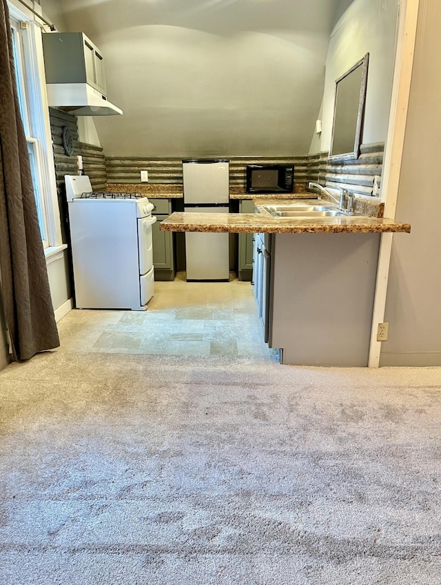 410 10th St SW, Willmar, MN 56201 - kitchen featuring white range with gas stovetop, freestanding refrigerator, black microwave, under cabinet range hood, and light carpet