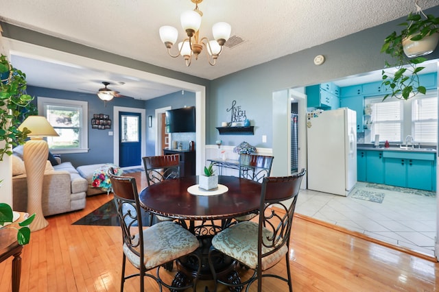 938 38th Ave N, Saint Cloud, MN 56303 - dining room featuring a chandelier, light wood finished floors, ceiling fan, and a textured ceiling