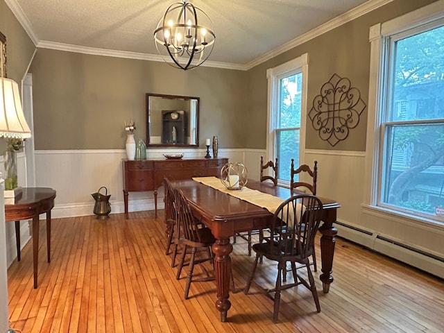 3128 Portland Ave, Minneapolis, MN 55407 - dining area featuring light wood finished floors, a wainscoted wall, a chandelier, a baseboard radiator, and ornamental molding