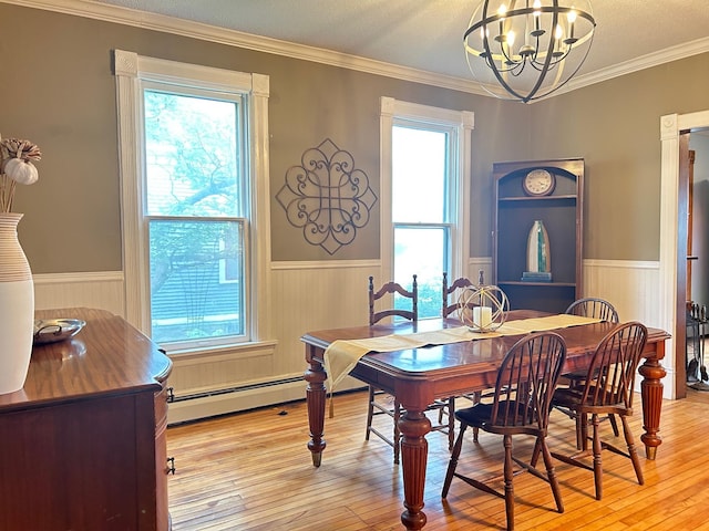 3128 Portland Ave, Minneapolis, MN 55407 - dining space with a wainscoted wall, baseboard heating, a chandelier, light wood-style floors, and ornamental molding
