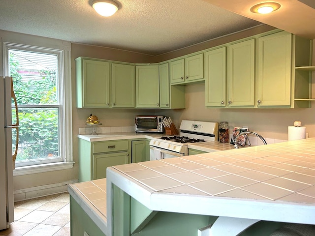 3128 Portland Ave, Minneapolis, MN 55407 - kitchen with green cabinets, white appliances, tile counters, healthy amount of natural light, and a textured ceiling