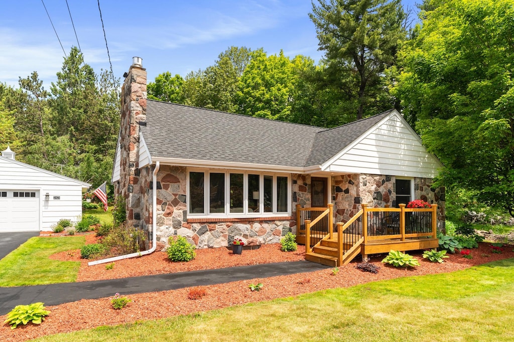 2821 Harvey St, Duluth, MN 55811 - view of front of home featuring stone siding, a shingled roof, a wooden deck, a chimney, and a garage