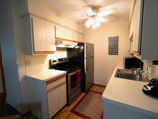 2720 Dale St N Unit C206, Roseville, MN 55113 - kitchen with appliances with stainless steel finishes, ceiling fan, wood finished floors, under cabinet range hood, and light countertops
