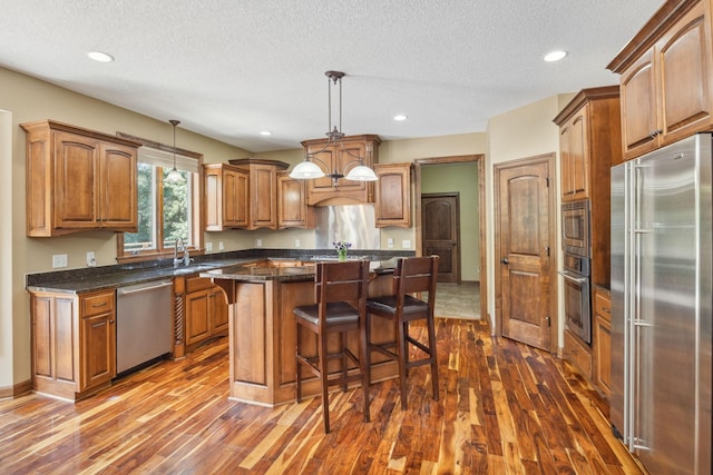18658 Ponderosa Ct, Eden Prairie, MN 55347 - kitchen with stainless steel appliances, dark wood finished floors, a kitchen breakfast bar, a textured ceiling, and a center island