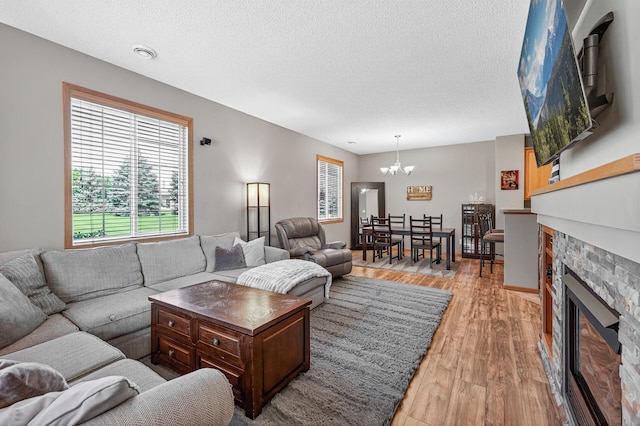 14220 Avalon Path Unit 1102, Rosemount, MN 55068 - living area featuring a chandelier, healthy amount of natural light, light wood-style flooring, a stone fireplace, and a textured ceiling