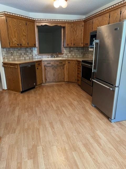 324 7th St, Windom, MN 56101 - kitchen featuring stainless steel appliances, brown cabinetry, light wood-style flooring, and light countertops