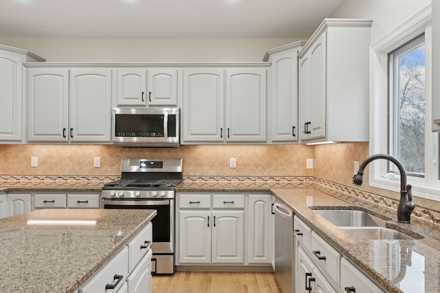 4584 162nd Ln NW, Andover, MN 55304 - kitchen featuring stainless steel appliances, white cabinetry, light wood-style floors, light stone counters, and decorative backsplash