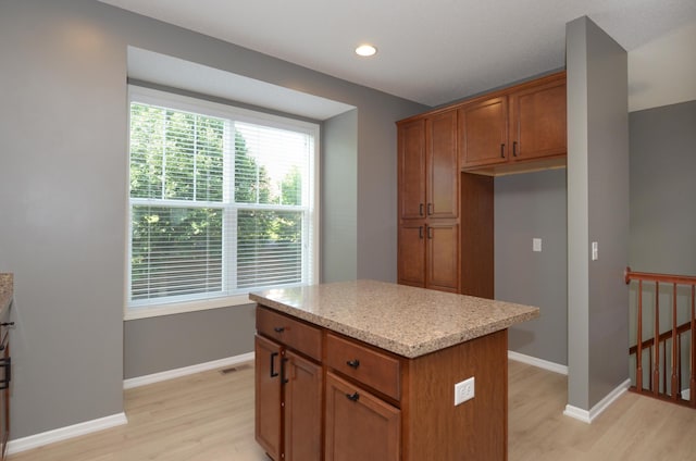 8397 Norwood Ln N, Maple Grove, MN 55311 - kitchen featuring light wood-style floors, a kitchen island, brown cabinets, recessed lighting, and light stone counters